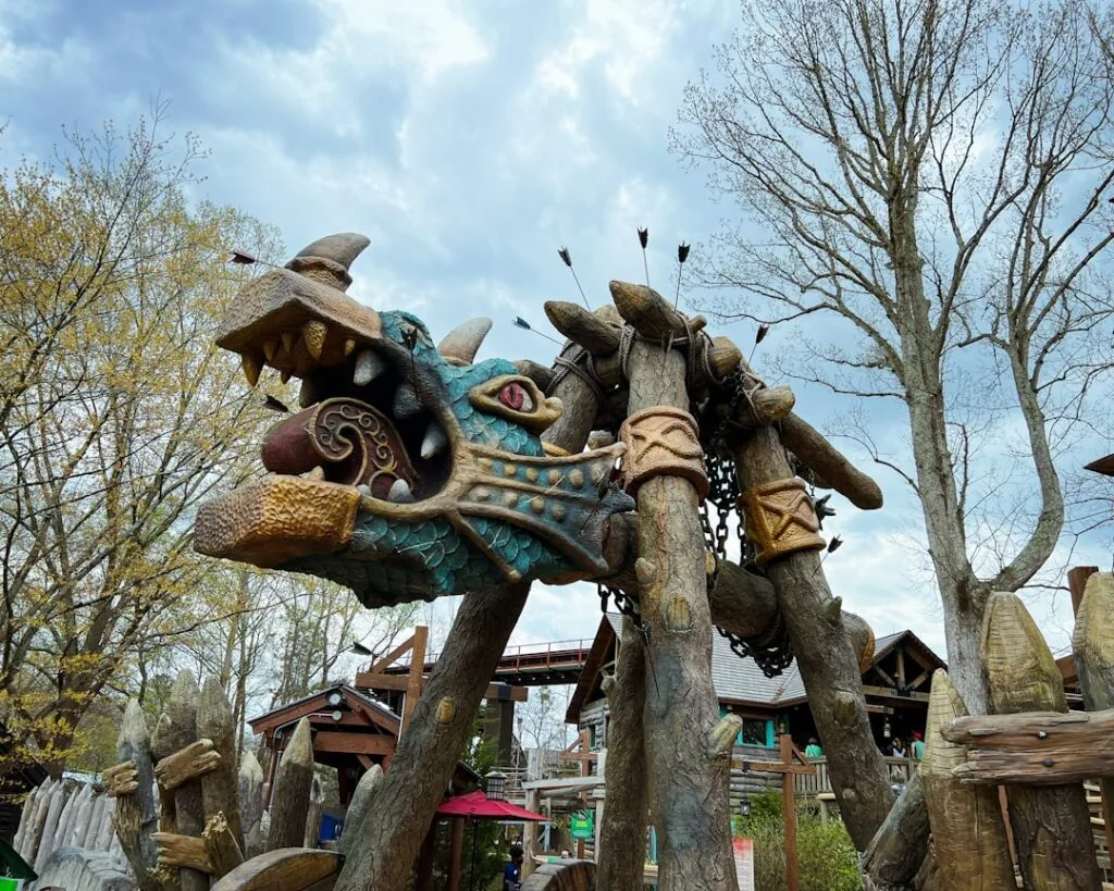 Carved dragon head sculpture pierced by arrows in wooden playground