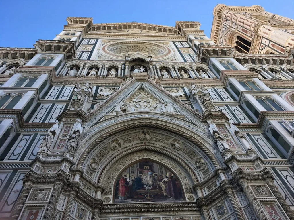 Ornate marble facade of Florence Duomo with detailed sculptures above