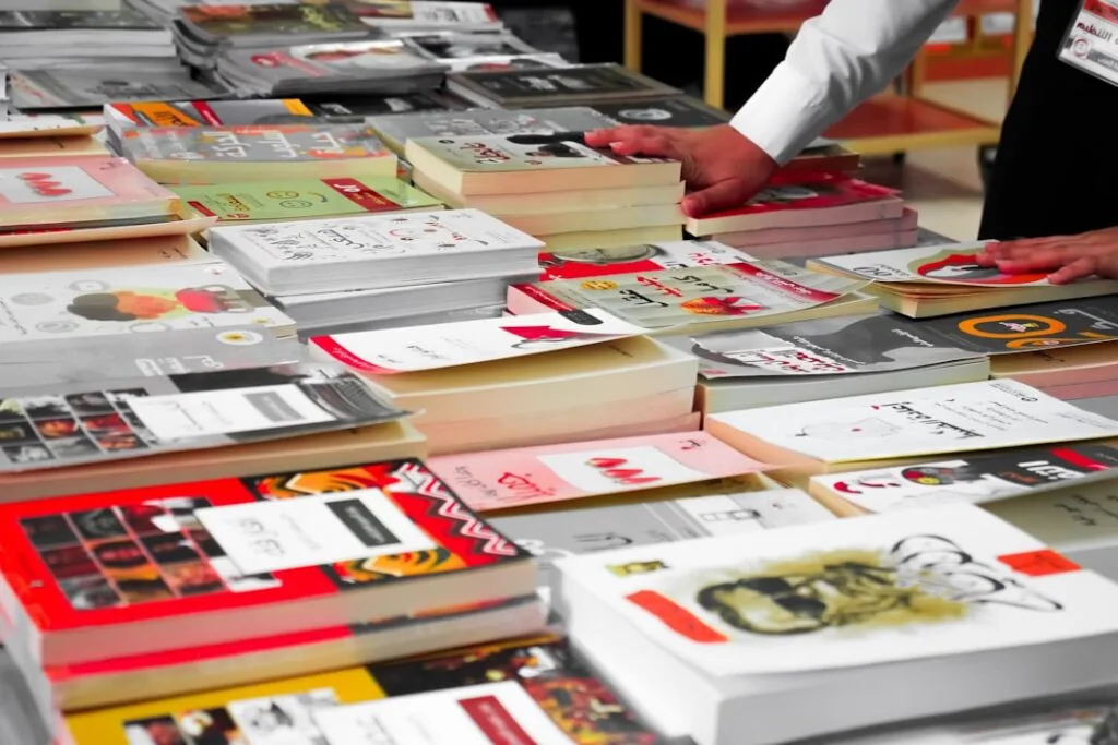 Hands arranging stacks of books on a market table at Lucca event