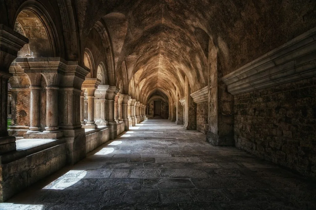Sunlit stone cloister arcade with repeating arches inside Lucca church complex