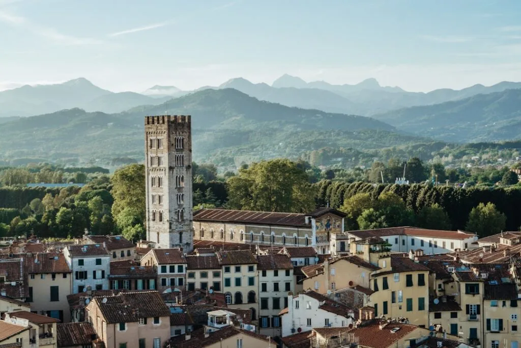 Medieval bell tower rising above Lucca rooftops with mountainous backdrop