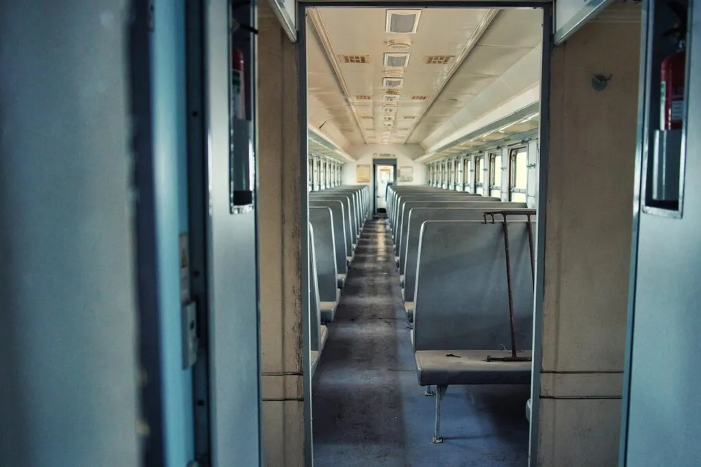 Empty regional train carriage aisle with rows of gray vinyl seats