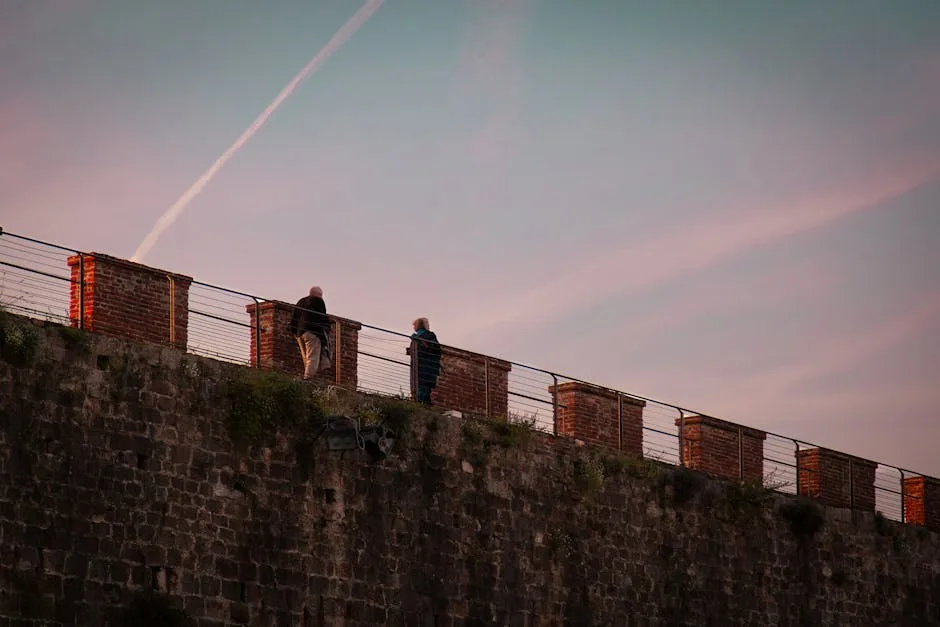 Two people leaning on Lucca's ancient city wall at dusk.