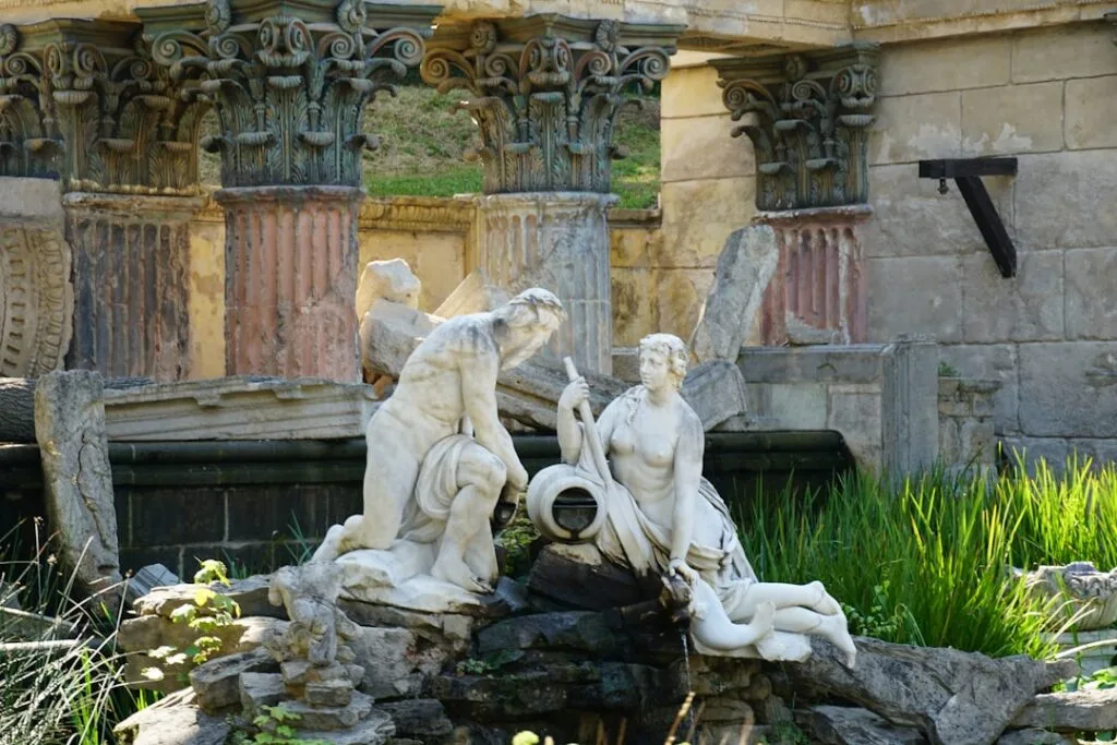Marble fountain sculptures among ruins in a Lucca garden setting.