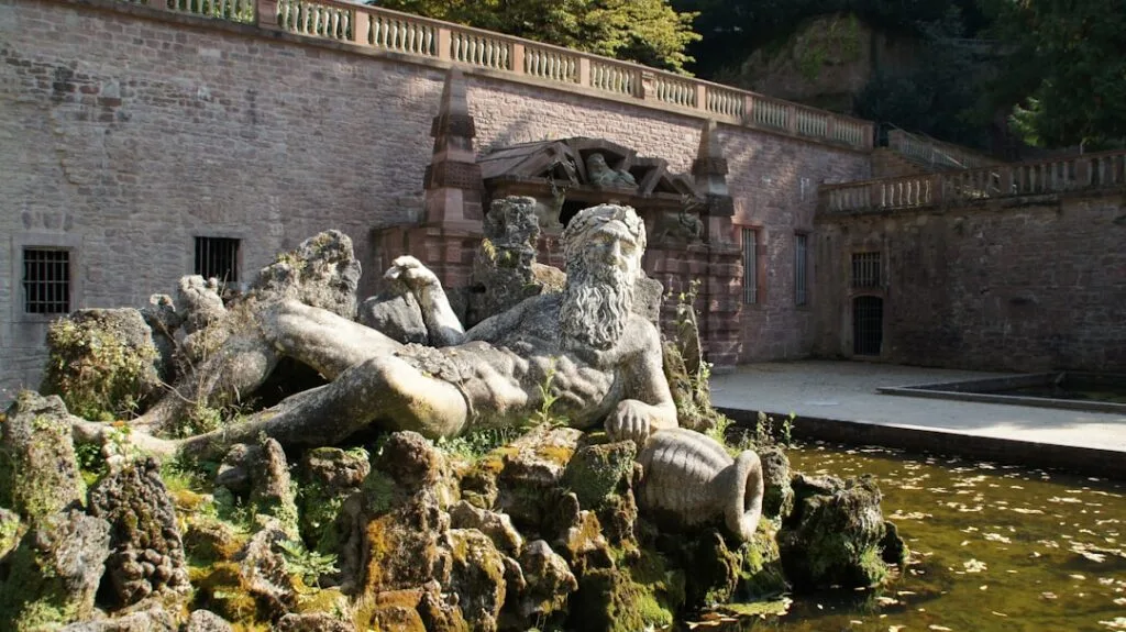 Ornate stone fountain sculpture in Lucca courtyard beside water basin