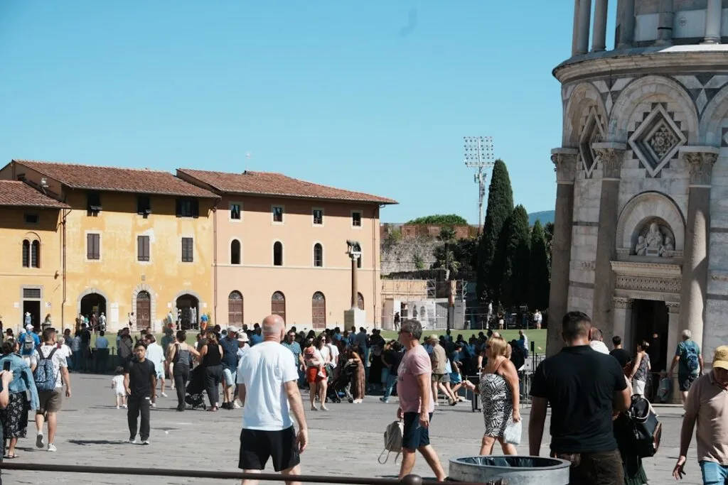 Tourists walking near Pisa cathedral and baptistery, busy square