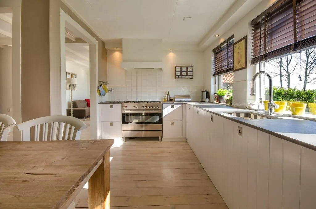 Sunlit Lucca apartment kitchen with wooden table and stainless stove.