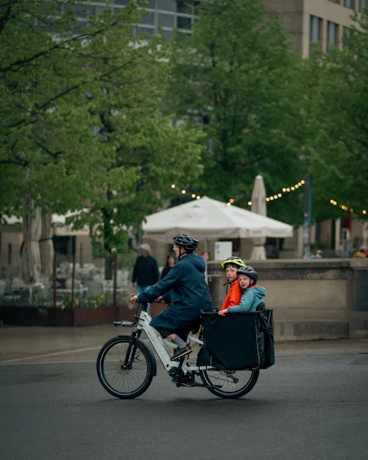 Adult pedals cargo bike carrying two helmeted children through Lucca streets