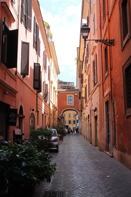 Sunlit narrow Italian alleyway lined with shutters and arch