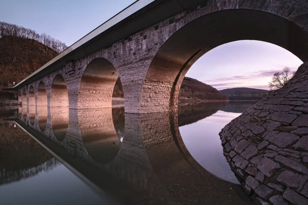 Arched stone bridge reflected in still water near Bagni di Lucca