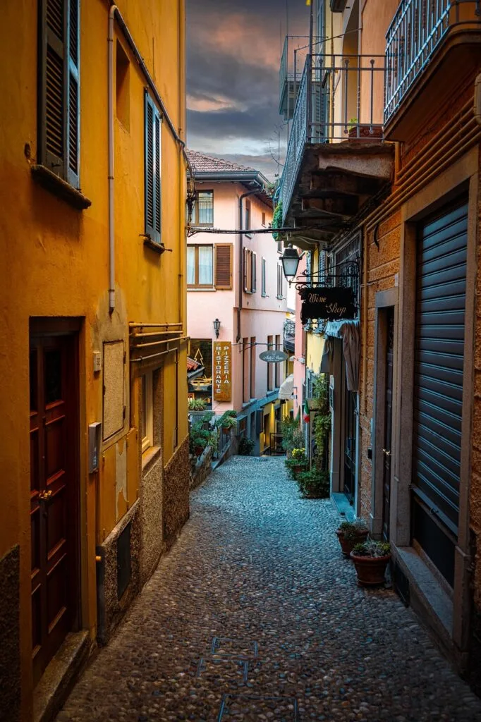 Narrow cobblestone alley lined with colorful shops in Lucca
