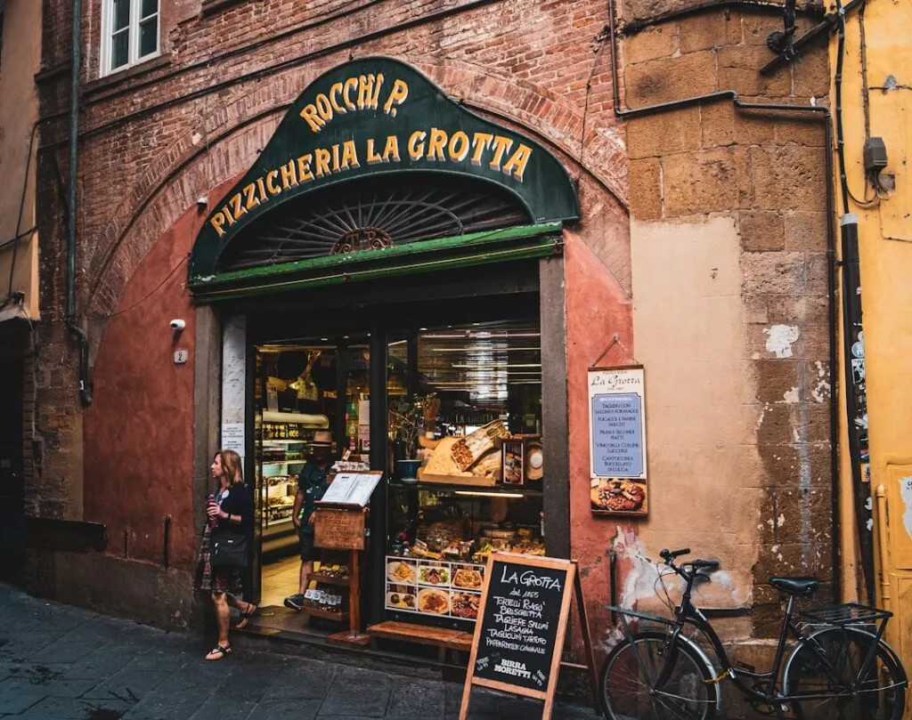 Rustic Lucca pizzeria La Grotta storefront with bicycle and passerby
