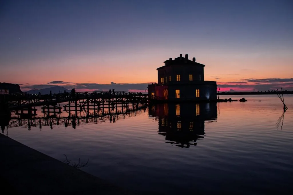 Boathouse on wooden pier at twilight, water reflections and silhouettes