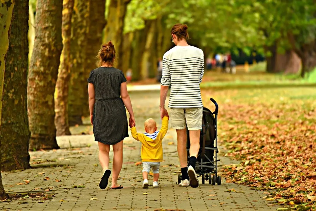 Parents and toddler walking a leafy pathway on Lucca walls