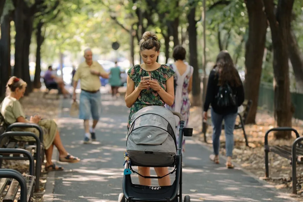 Woman pushing a stroller along shaded Lucca tree-lined promenade