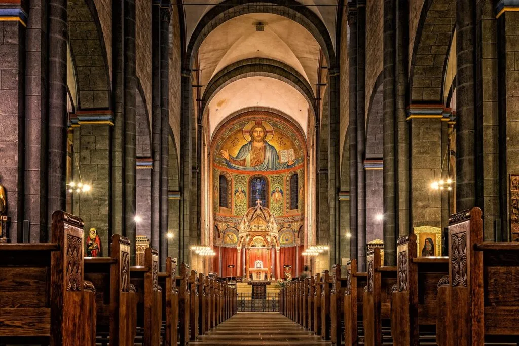 Long nave of a Lucca church with wooden pews and mosaic apse