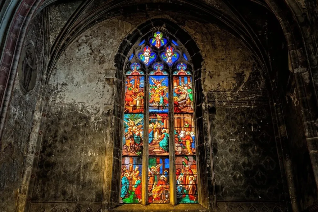 Stained glass window depicting biblical scenes in Lucca church's weathered wall