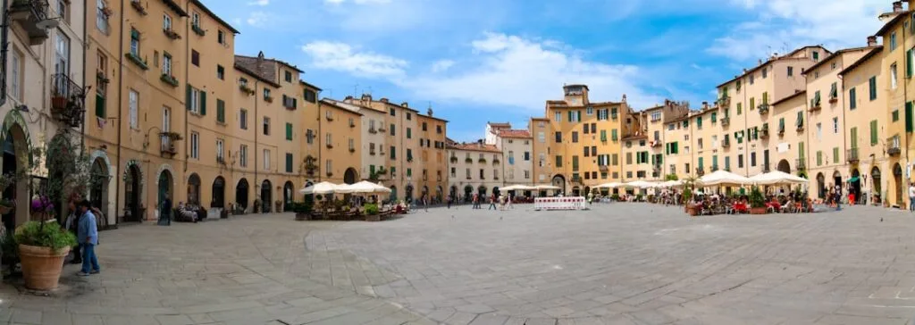 Oval medieval piazza in Lucca lined with yellow buildings and cafes